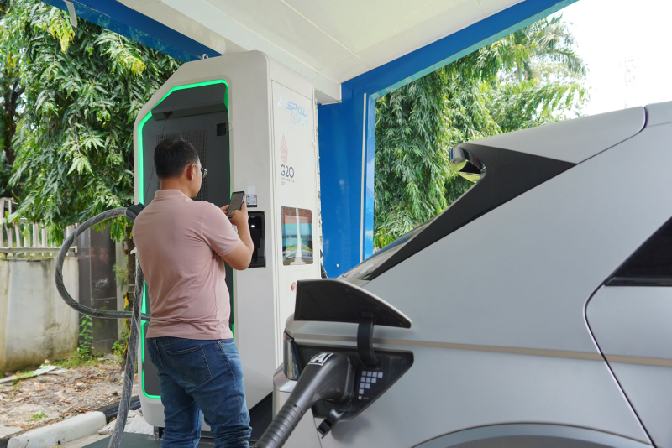 Pemilik kendaraan listrik saat melakukan scan barcode untuk pengisian kendaraan listrik menjelang libur Iduladha.